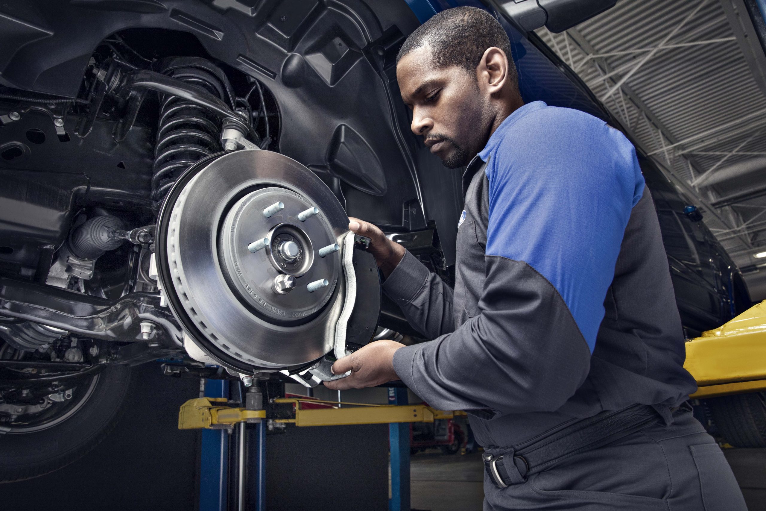 Technician inspecting and servicing vehicle brakes.