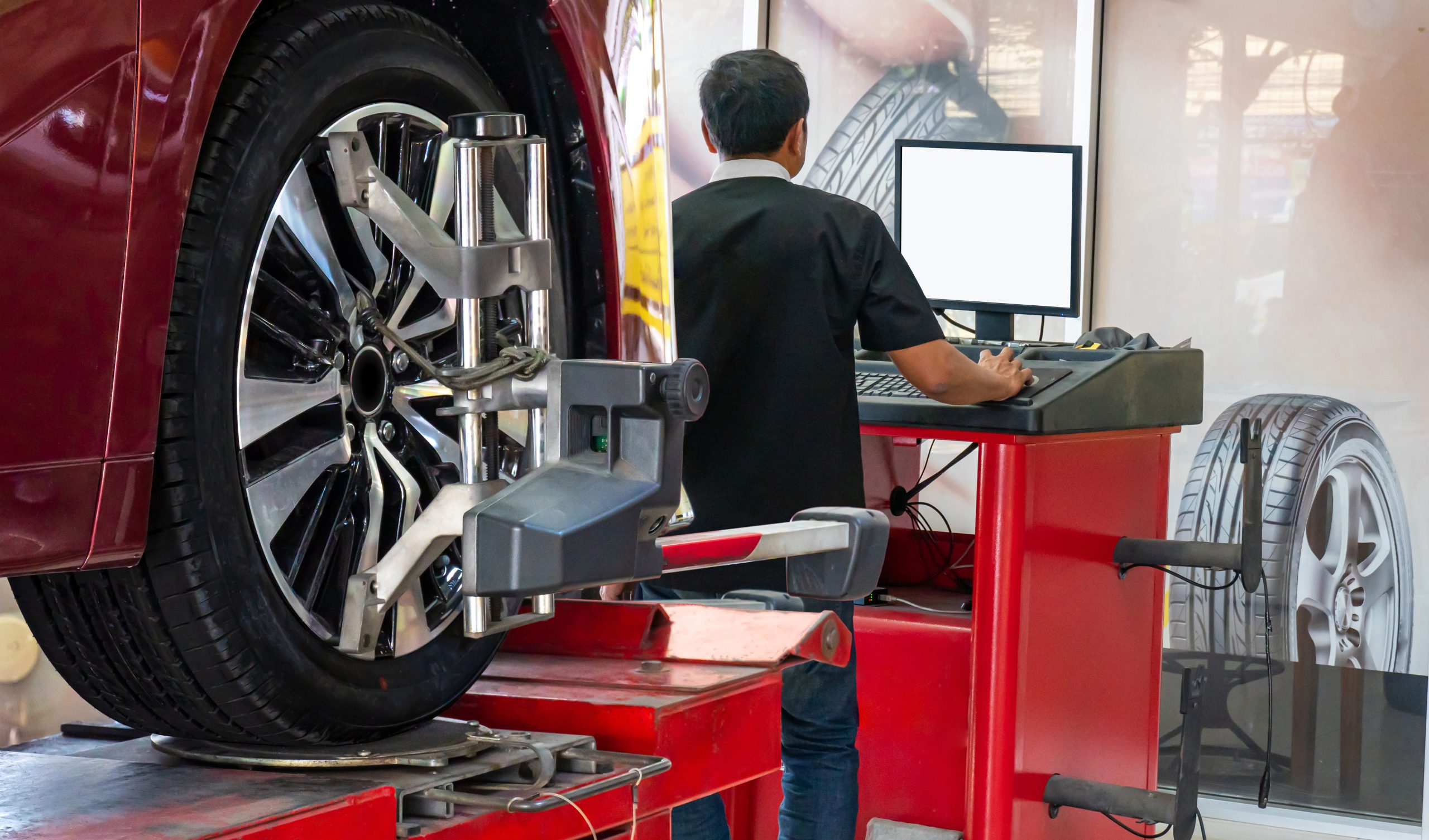 Technician performing wheel alignment on a car tire
