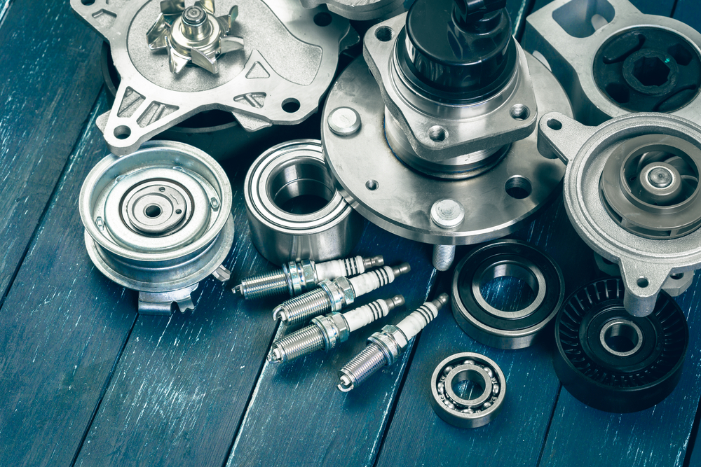 Assorted automotive engine parts and spark plugs arranged on a workbench.