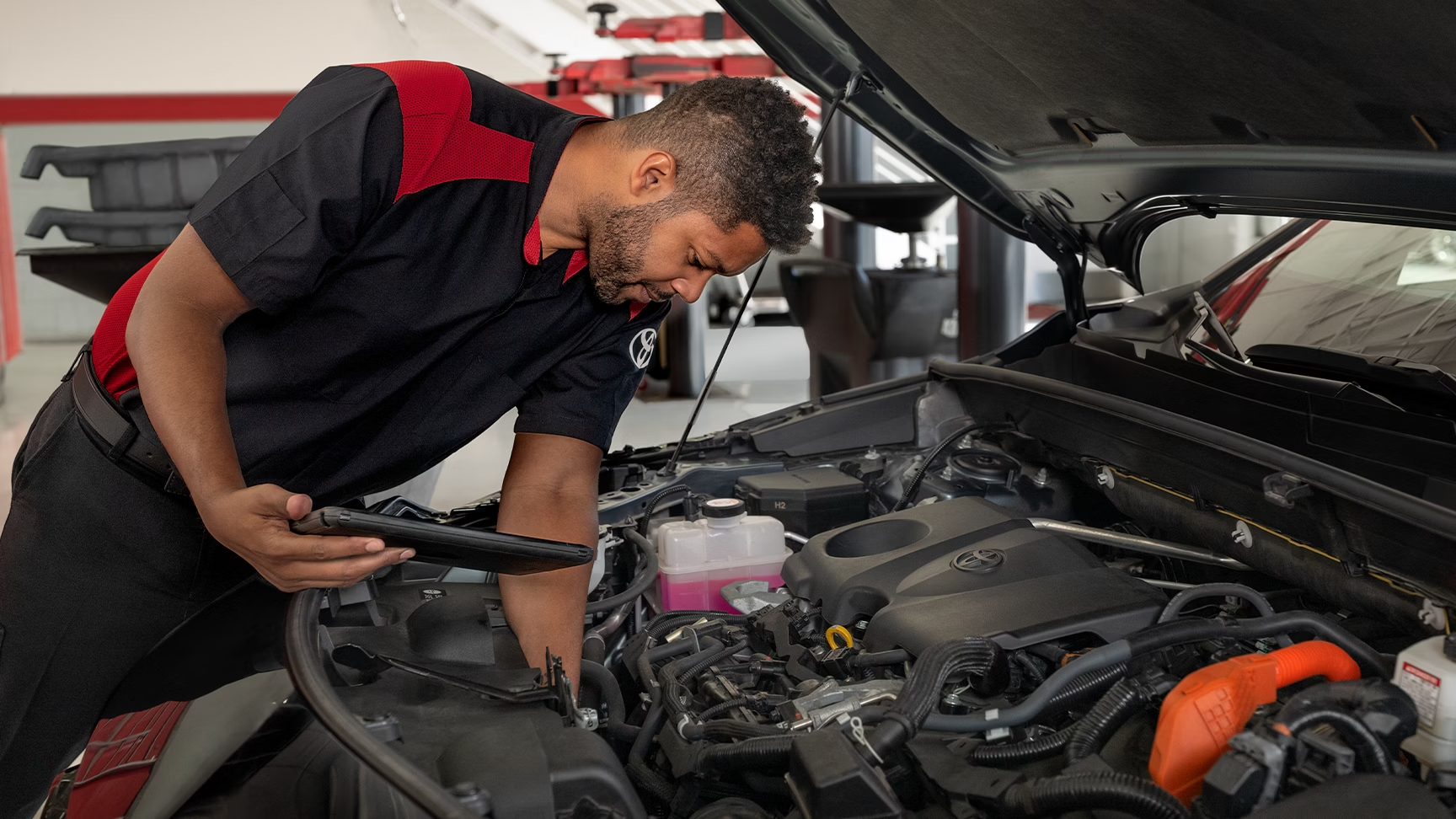 Toyota technician inspecting engine during service.